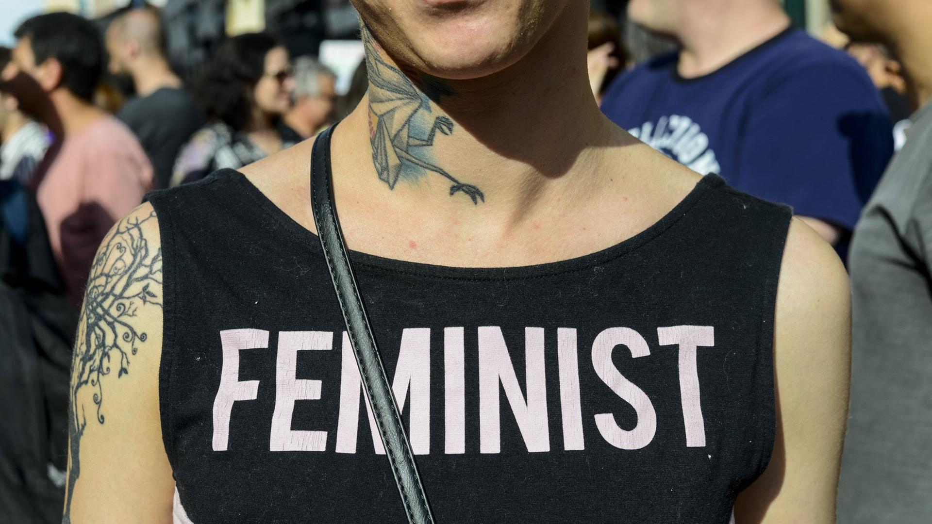Eine junge Frau trägt ein T-Shirt mit der Aufschriftin "Feministin" Eine junge Frau trägt ein T-Shirt mit der Aufschriftin "Feministin"