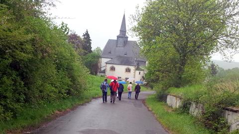 Besuchergruppe des "Eckweilerer Sommers", ein Kulturprogramm in Rheinland-Pfalz, auf dem Weg zur Heilig-Kreuz-Kirche im Hunsrück.