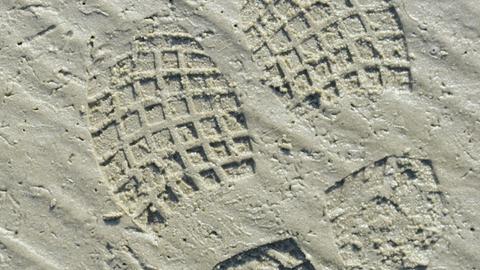 Menschen hinterlassen feine Spuren im Sand am Meer