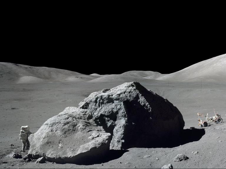 Ein Astronaut neben einem Felsen auf dem Mond