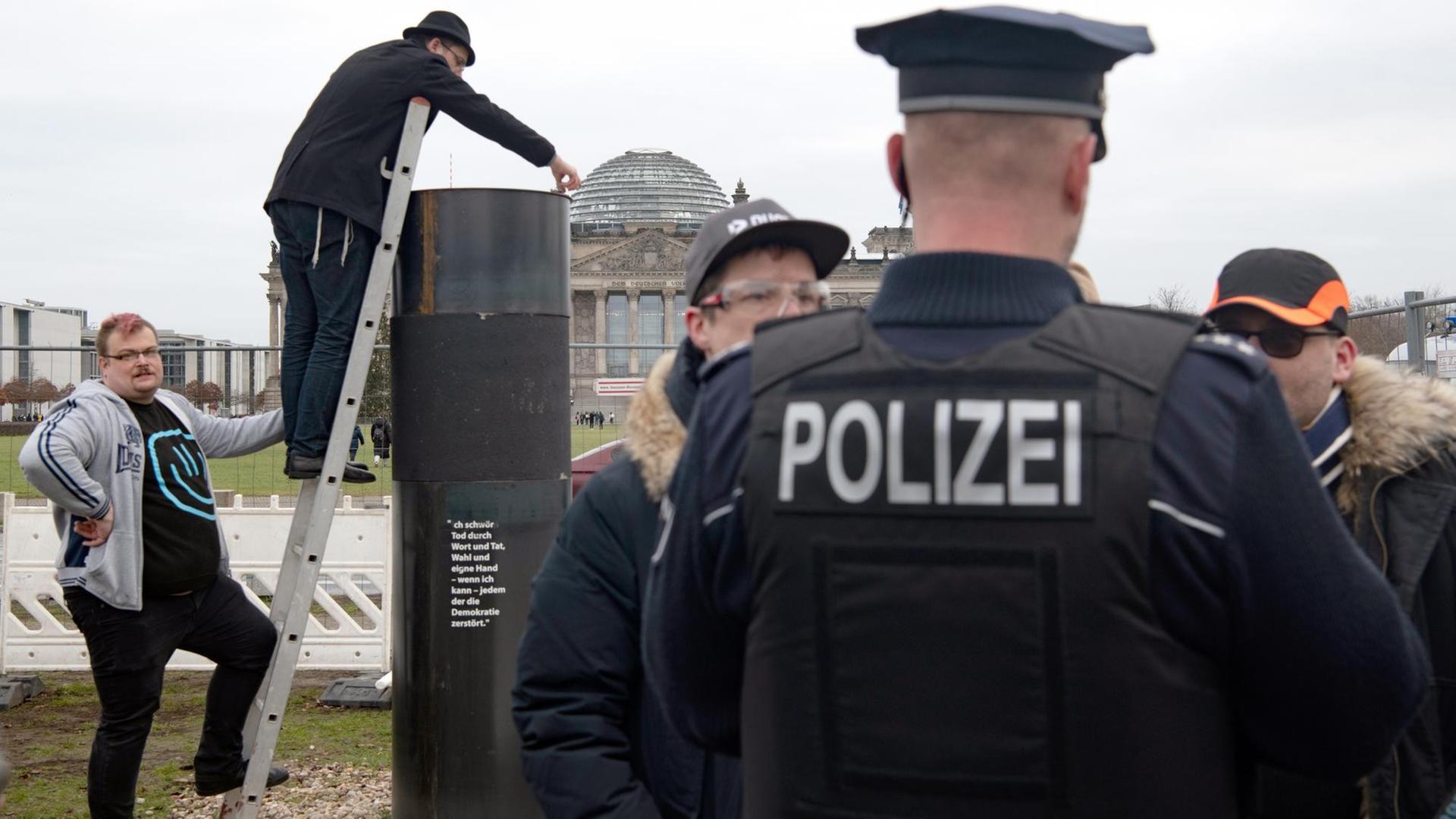 Der Autor Eliyah Havemann (2.v.l.) befestigt, auf einer Leiter stehend, eine zuvor abmontierte Stahlplatte wieder auf der umstrittene Stahlsäule des Künstlerkollektivs "Zentrum für politische Schönheit" (ZPS) gegenüber dem Reichstagsgebäude. Mehrere Aktivisten haben versucht, die umstrittene Stahlsäule des Künstlerkollektivs in Berlin abzubauen. Der Autor Eliyah Havemann (2.v.l.) befestigt, auf einer Leiter stehend, eine zuvor abmontierte Stahlplatte wieder auf der umstrittene Stahlsäule des Künstlerkollektivs "Zentrum für politische Schönheit" (ZPS) gegenüber dem Reichstagsgebäude. Mehrere Aktivisten haben versucht, die umstrittene Stahlsäule des Künstlerkollektivs in Berlin abzubauen.
