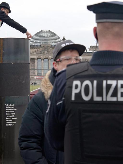 Der Autor Eliyah Havemann (2.v.l.) befestigt, auf einer Leiter stehend, eine zuvor abmontierte Stahlplatte wieder auf der umstrittene Stahlsäule des Künstlerkollektivs "Zentrum für politische Schönheit" (ZPS) gegenüber dem Reichstagsgebäude. Mehrere Aktivisten haben versucht, die umstrittene Stahlsäule des Künstlerkollektivs in Berlin abzubauen.