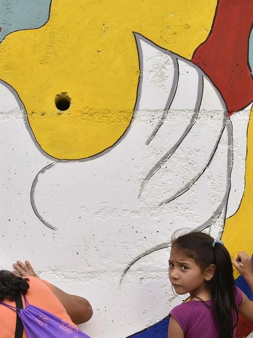 Frauen und Kinder malen ein Wandbild mit einer Taube an der Straße nach Planadas in Kolumbien.