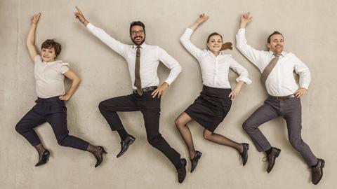 Menschen in Businesskleidung liegen auf dem Rücken, als würden sie durchs Büro tanzen