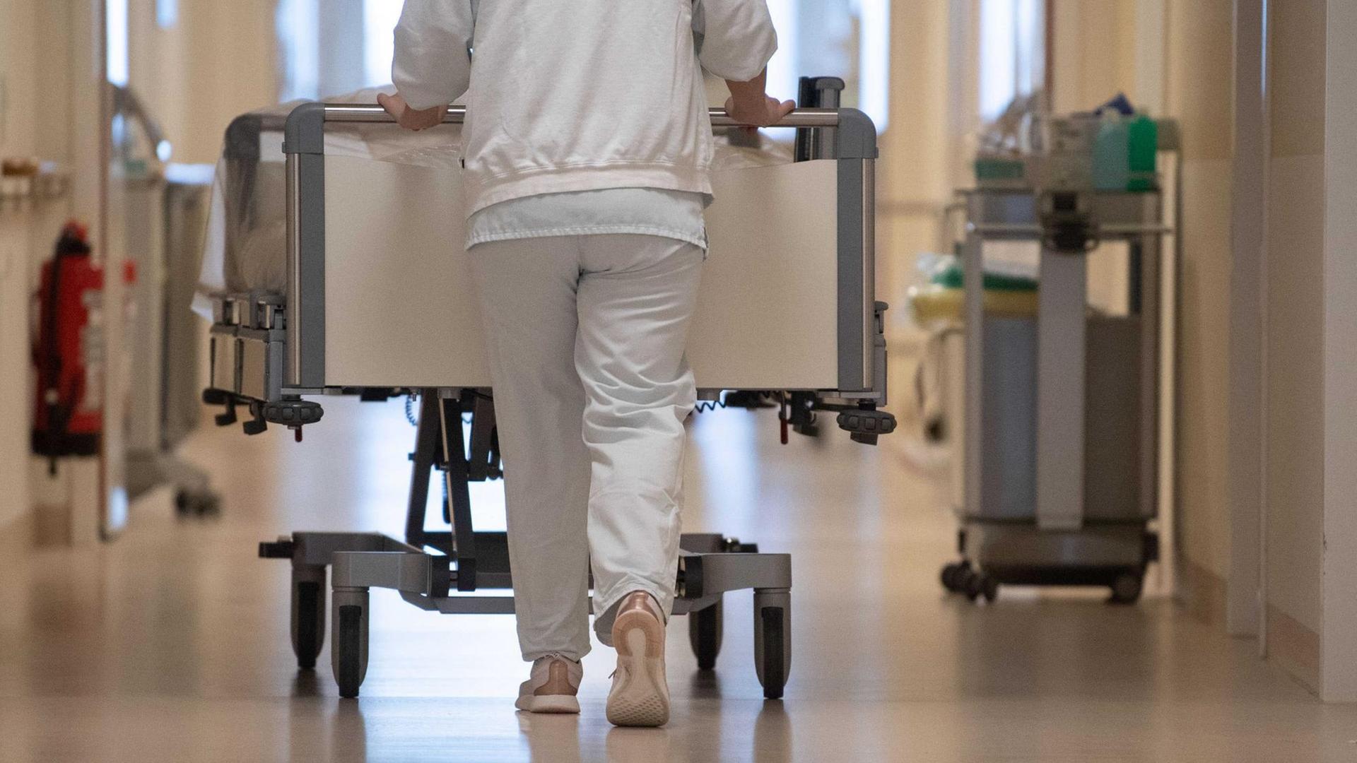 Eine Krankenpflegerin schiebt ein Krankenbett durch einen Flur. Eine Krankenpflegerin schiebt ein Krankenbett durch einen Flur.