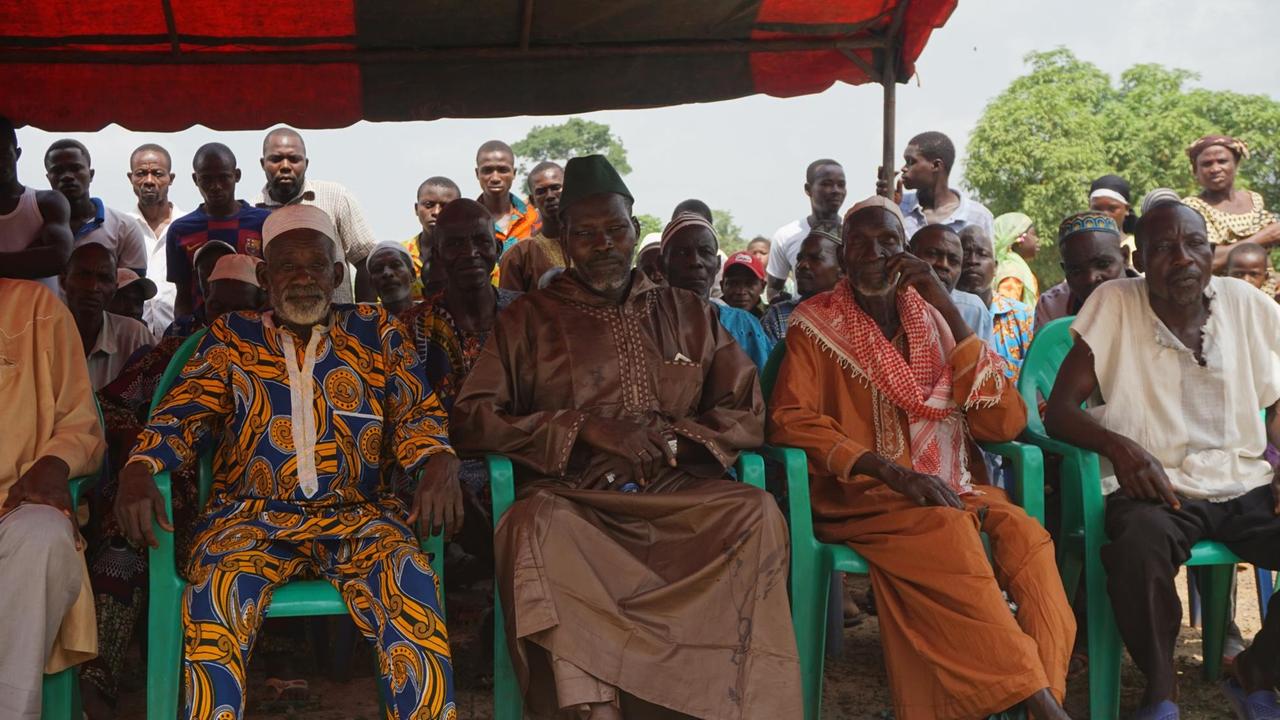 Dorfversammlung mit Männern, die bunte afrikanische Kleidung tragen. Dorfversammlung mit Männern, die bunte afrikanische Kleidung tragen.