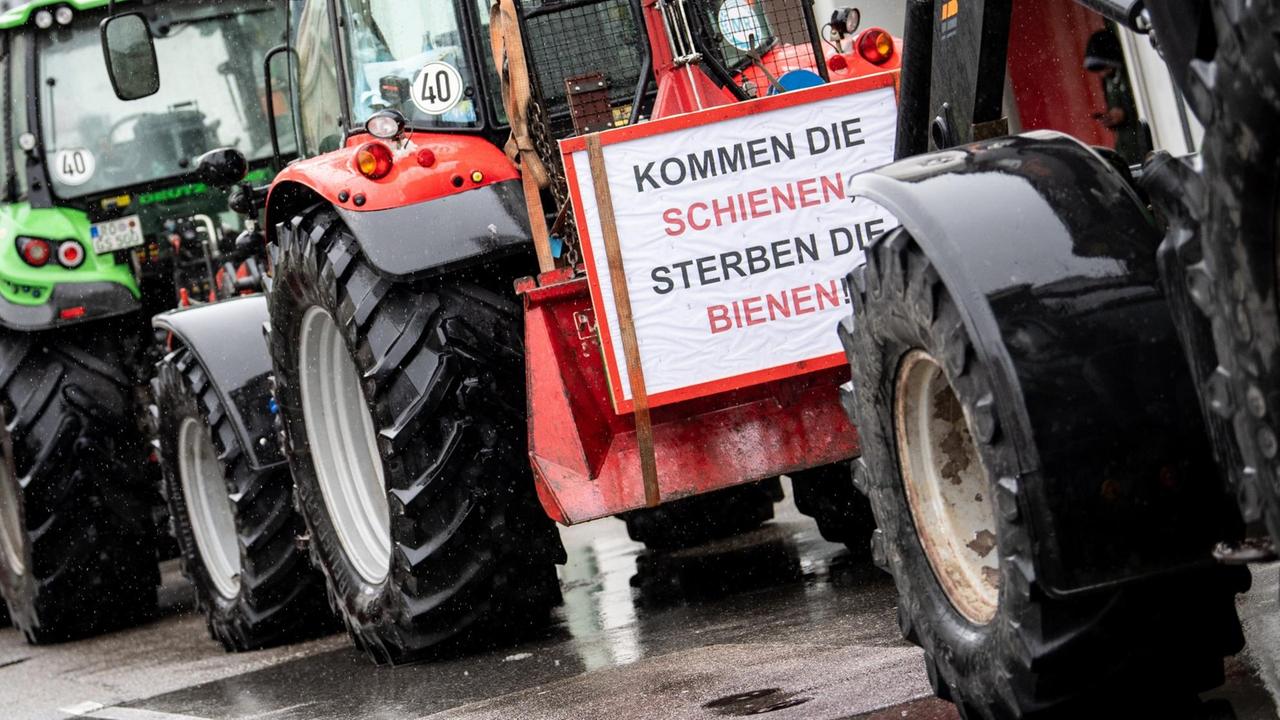 Landwirte nehmen mit Traktoren an einer Demonstration gegen den Brenner-Nordzulauf teil. An einem Schlepper ist ein Schild mit der Aufschrift «Kommen die Schienen, sterben die Bienen» befestigt.
