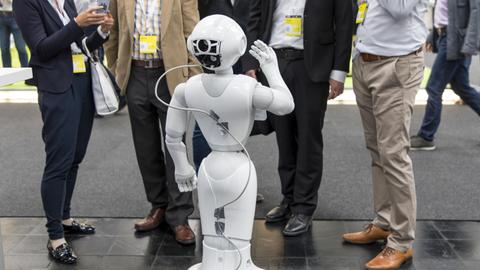 Auf der Messe CEBIT steht ein SoftBank Roboter in einer Gruppe von Menschen.