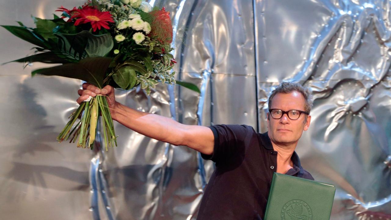 Der deutsche Schriftsteller Tex Rubinowitz, Gewinner des Ingeborg-Bachmann-Preises 2014, mit Blumenstrauß bei der Preisverleihung der 38. Tage der deutschsprachigen Literatur in Klagenfurt.