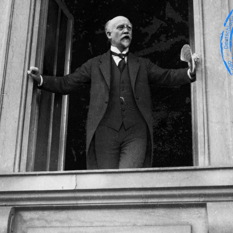 Philipp Scheidemann steht an einem Fenster und richtet sich an eine im Bild nicht sichtbare Masse. Philipp Scheidemann steht an einem Fenster und richtet sich an eine im Bild nicht sichtbare Masse.