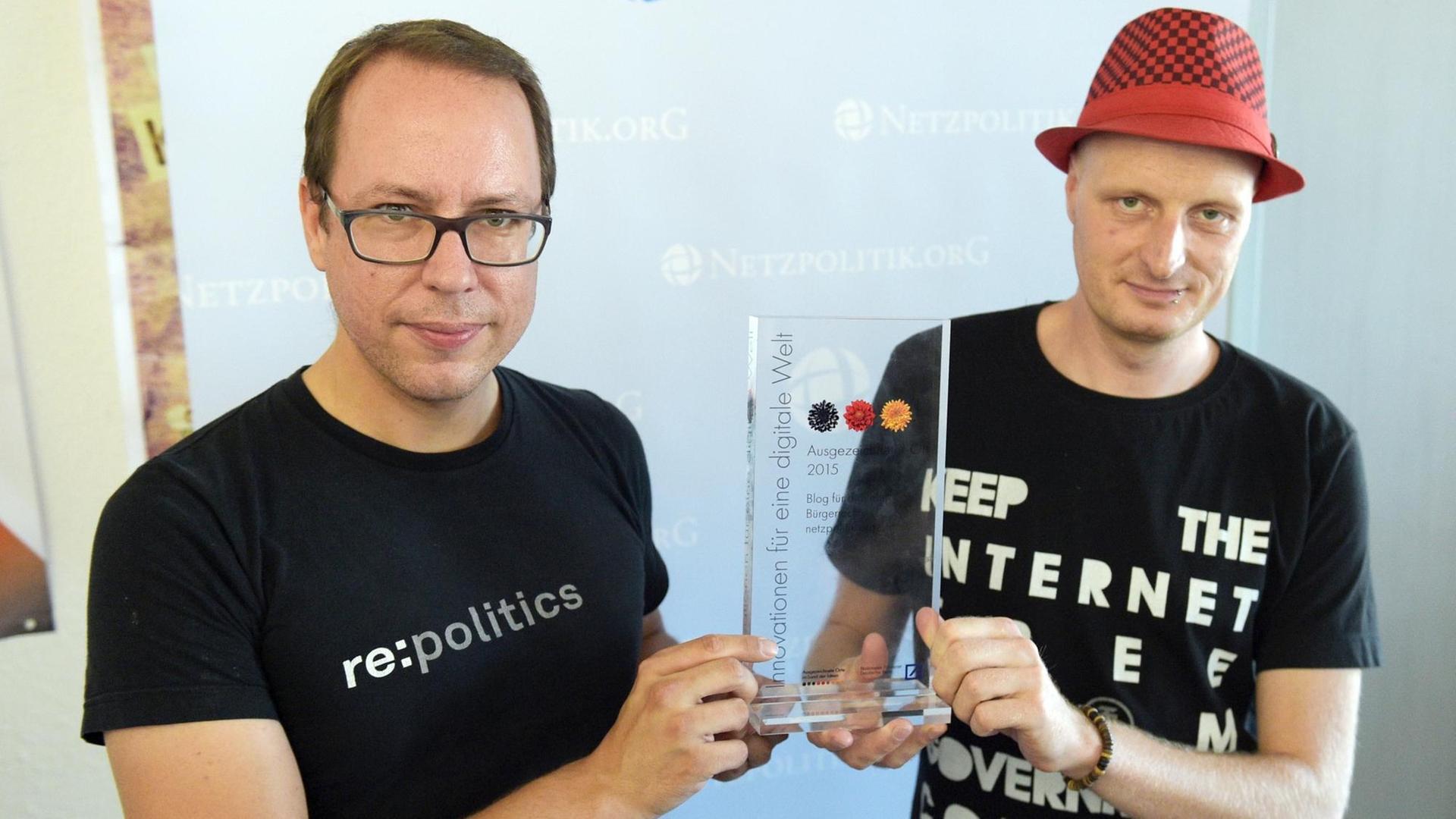 Markus Beckedahl und Andre Meister halten eine gläserne Auszeichnung zwischen sich in die Kamera Markus Beckedahl und Andre Meister halten eine gläserne Auszeichnung zwischen sich in die Kamera