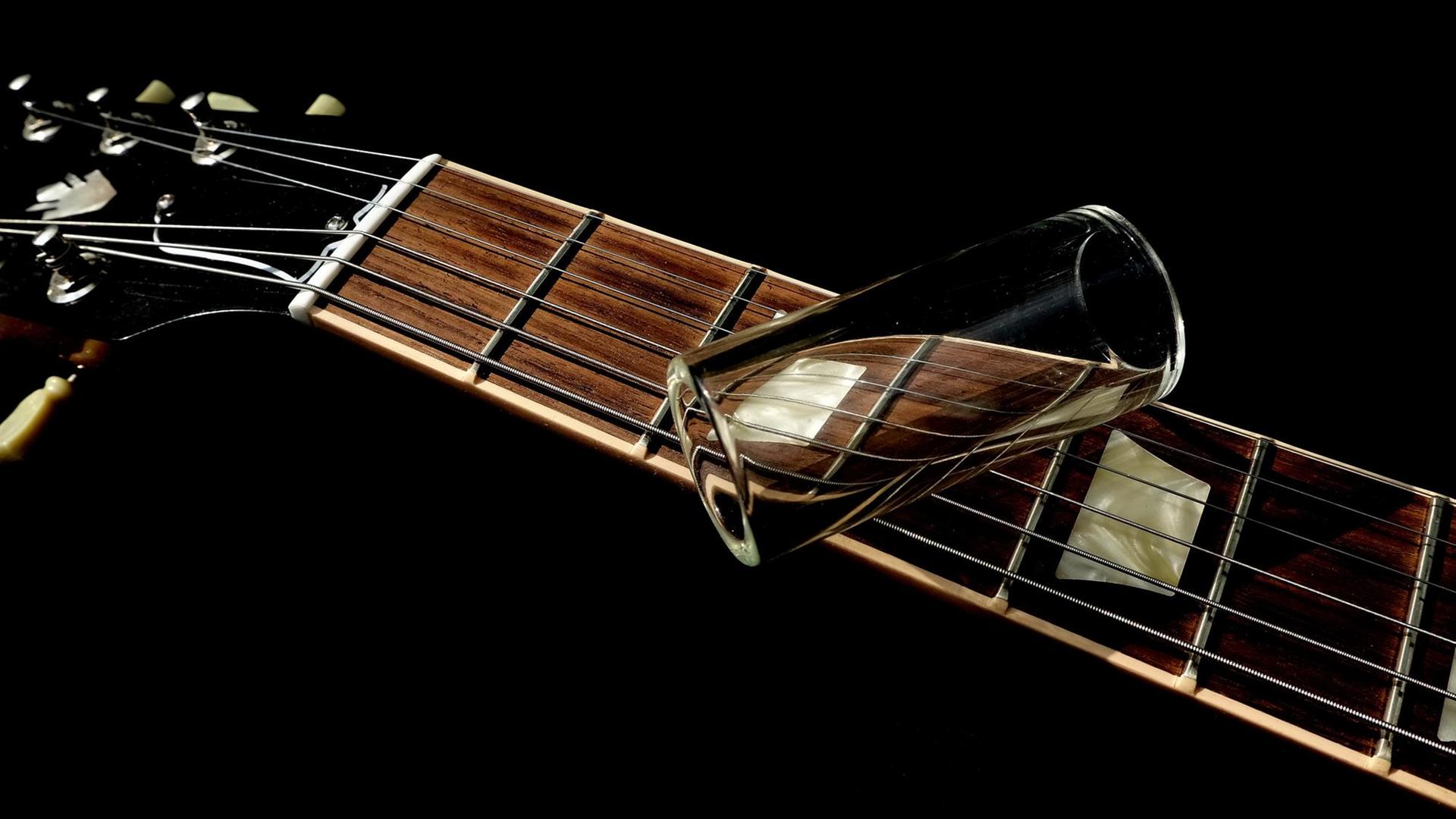 Ein Glasröhrchen liegt auf dem Hals einer elektrischen Gitarre. Ein Glasröhrchen liegt auf dem Hals einer elektrischen Gitarre.