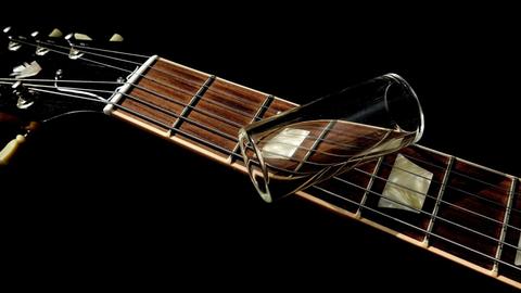 Ein Glasröhrchen liegt auf dem Hals einer elektrischen Gitarre.