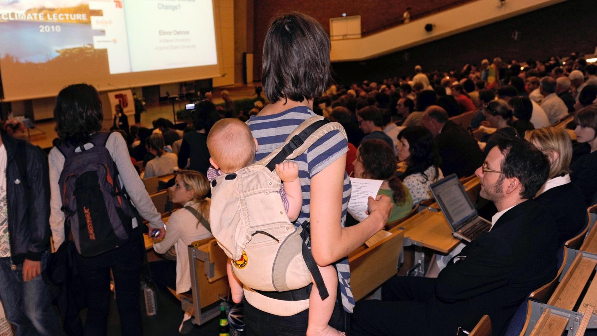 Einen Sitzplatz sucht eine Studentin mit Kind, die sich am Dienstag (22.06.2010) im Audimax in der Technischen Universität Berlin (TU Berlin) einen Vortrag im Rahmen der Climate Lecture 2010 anhören will. Die Nobelpreisträgerin Ostrom will laut Veranstalter mit dem Vortrag "Who Affects Climate Change" deutlich machen, dass die Fixierung auf ein globales Klimaschutzabkommen zu kurz greift. Foto: Rainer Jensen dpa/lbn | Verwendung weltweit Einen Sitzplatz sucht eine Studentin mit Kind, die sich am Dienstag (22.06.2010) im Audimax in der Technischen Universität Berlin (TU Berlin) einen Vortrag im Rahmen der Climate Lecture 2010 anhören will. Die Nobelpreisträgerin Ostrom will laut Veranstalter mit dem Vortrag "Who Affects Climate Change" deutlich machen, dass die Fixierung auf ein globales Klimaschutzabkommen zu kurz greift. Foto: Rainer Jensen dpa/lbn | Verwendung weltweit