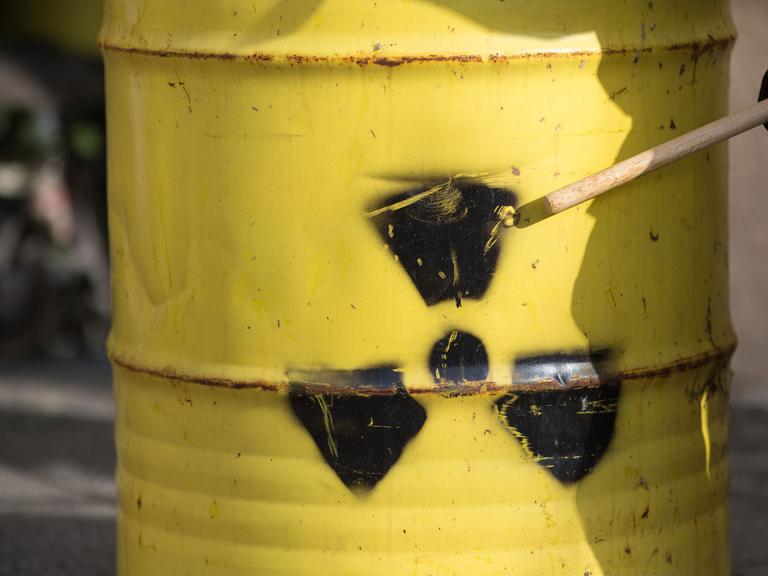 Ein Aktivist trommelt vor dem Bundesministerium für Umwelt, Bau und Reaktorsicherheit in Berlin auf einem Faß mit einem Warnzeichen für Radioaktivität.