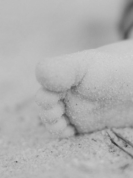 Der Fuß eines Kindes im Sand