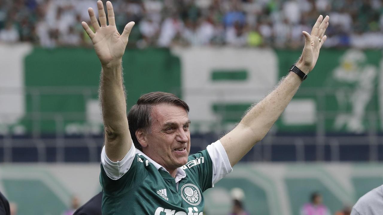 Bolsonaro geht über den Rasen und hat seine Arme hochgereckt. Bolsonaro geht über den Rasen und hat seine Arme hochgereckt.