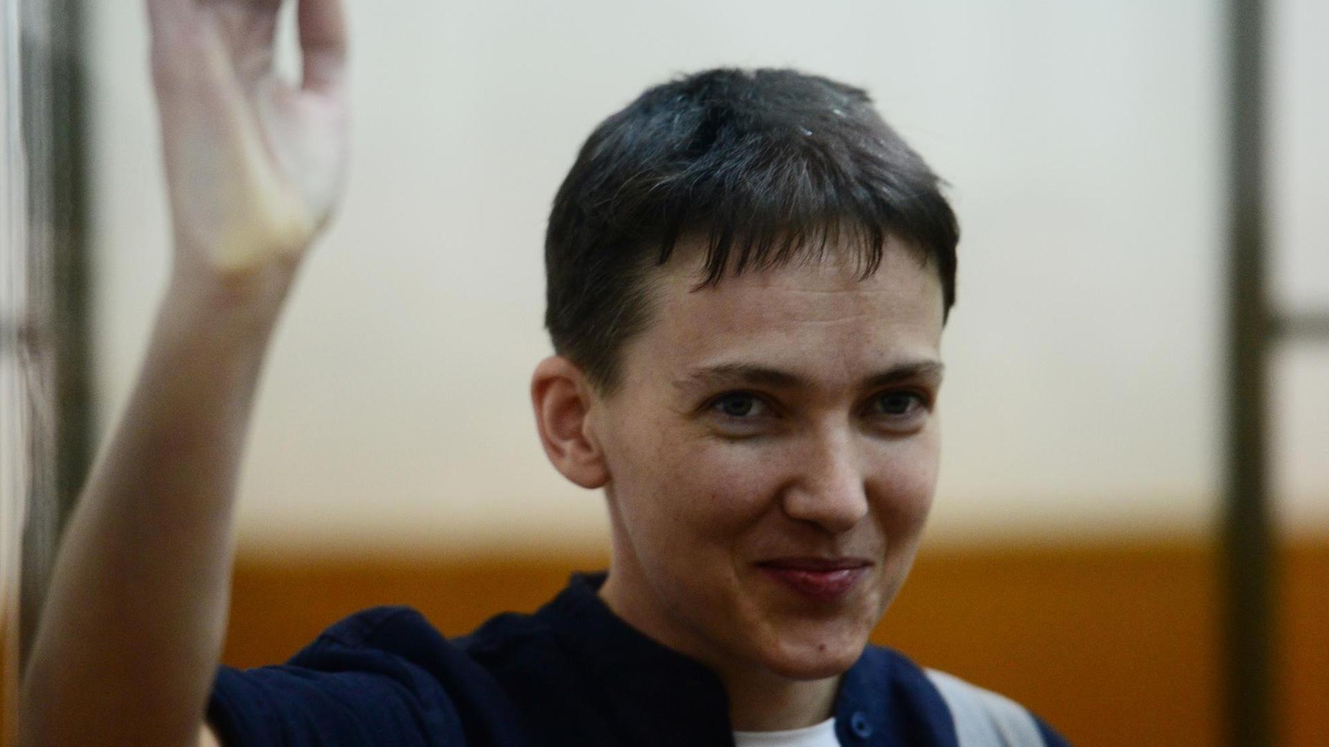 Die ukrainische Kampfpilotin Sawtschenko hebt während des Prozesses in Russland gegen sie winkend die Hand. Die ukrainische Kampfpilotin Sawtschenko hebt während des Prozesses in Russland gegen sie winkend die Hand.