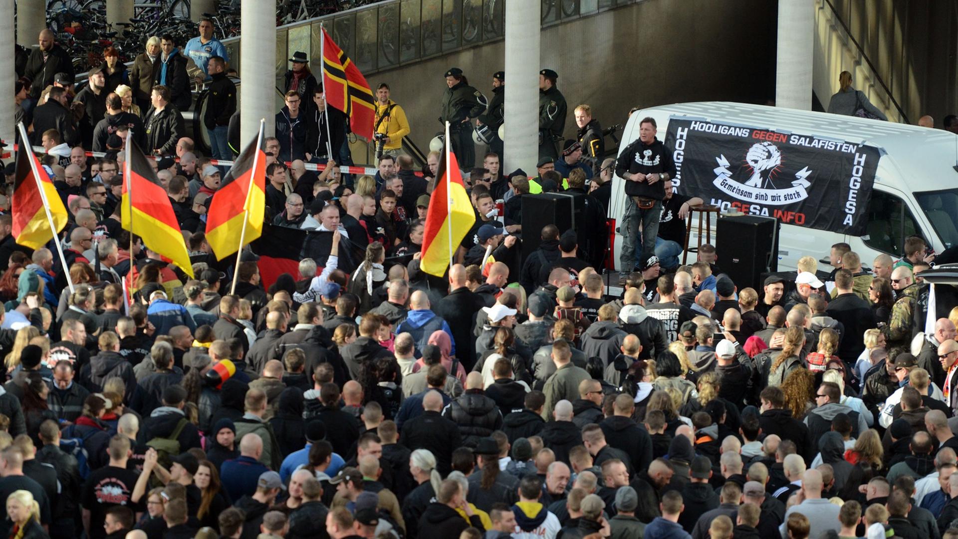 Demonstranten stehen am 26.10.2014 in Köln vor einem Fahrzeug mit einem Transparent der als gewaltbereit bekannten Gruppe "Hooligans gegen Salafisten". Demonstranten stehen am 26.10.2014 in Köln vor einem Fahrzeug mit einem Transparent der als gewaltbereit bekannten Gruppe "Hooligans gegen Salafisten".