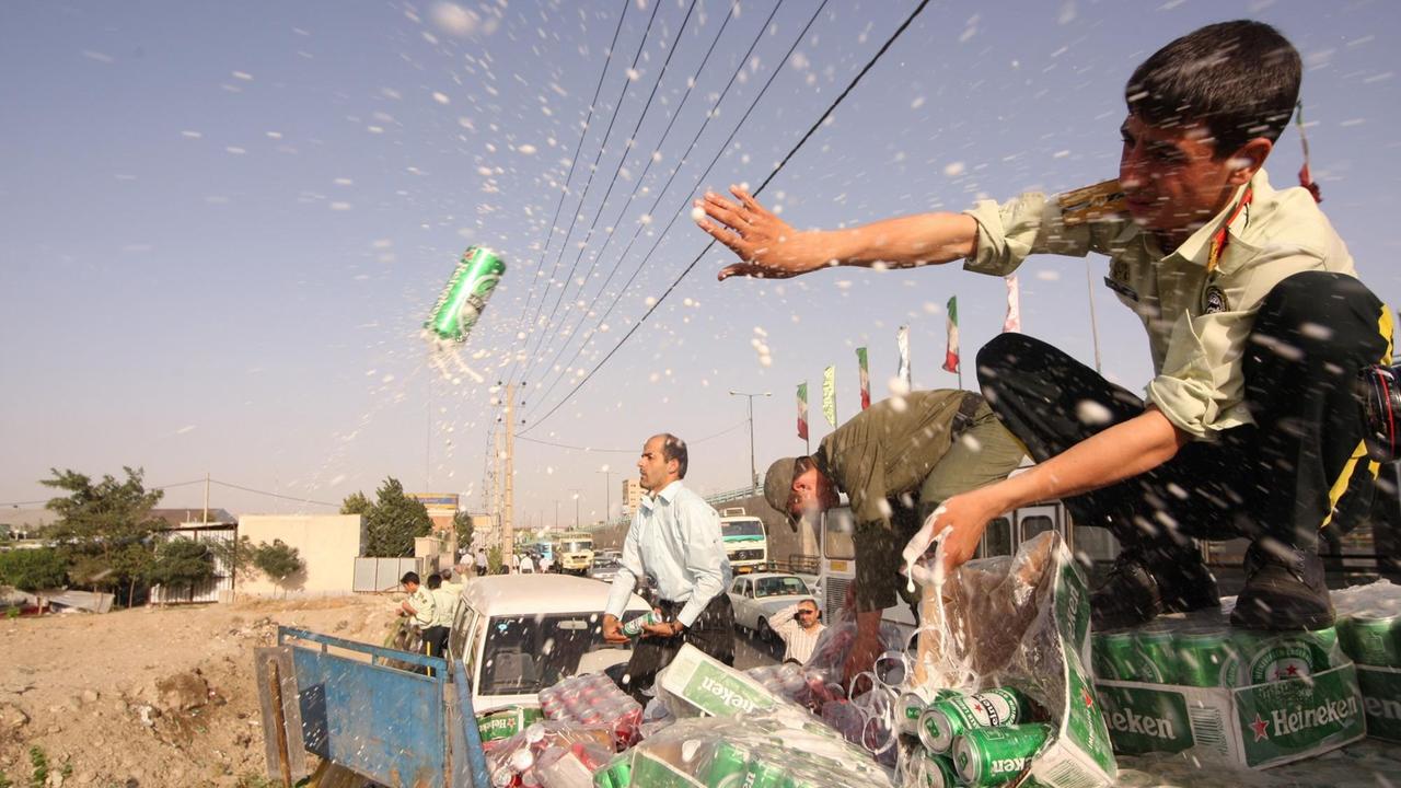 Iranische Polizisten gießen beschlagnahmte Bierdosen aus. Iranische Polizisten gießen beschlagnahmte Bierdosen aus.