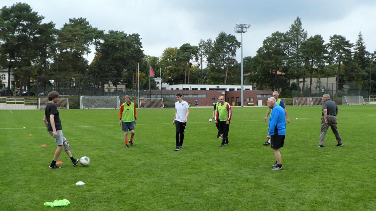 Ältere Männer spielen auf einem Fußballfeld Fußball.