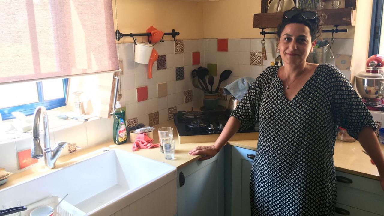 Gali Segev steht in ihrer Küche und lächelt in die Kamera Gali Segev steht in ihrer Küche und lächelt in die Kamera