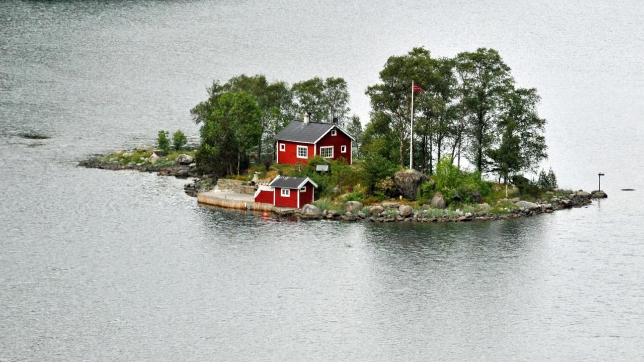 Eine Insel mit roten Holzhäusern in einem norwegischen Fjord Eine Insel mit roten Holzhäusern in einem norwegischen Fjord