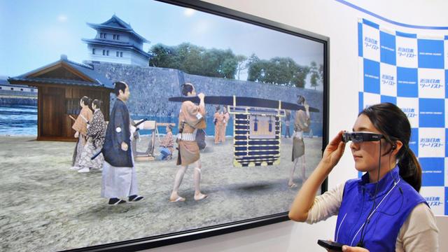 Eine Frau testet mit einer virtual reality Brille ein Angebot für Touristen in Japan.