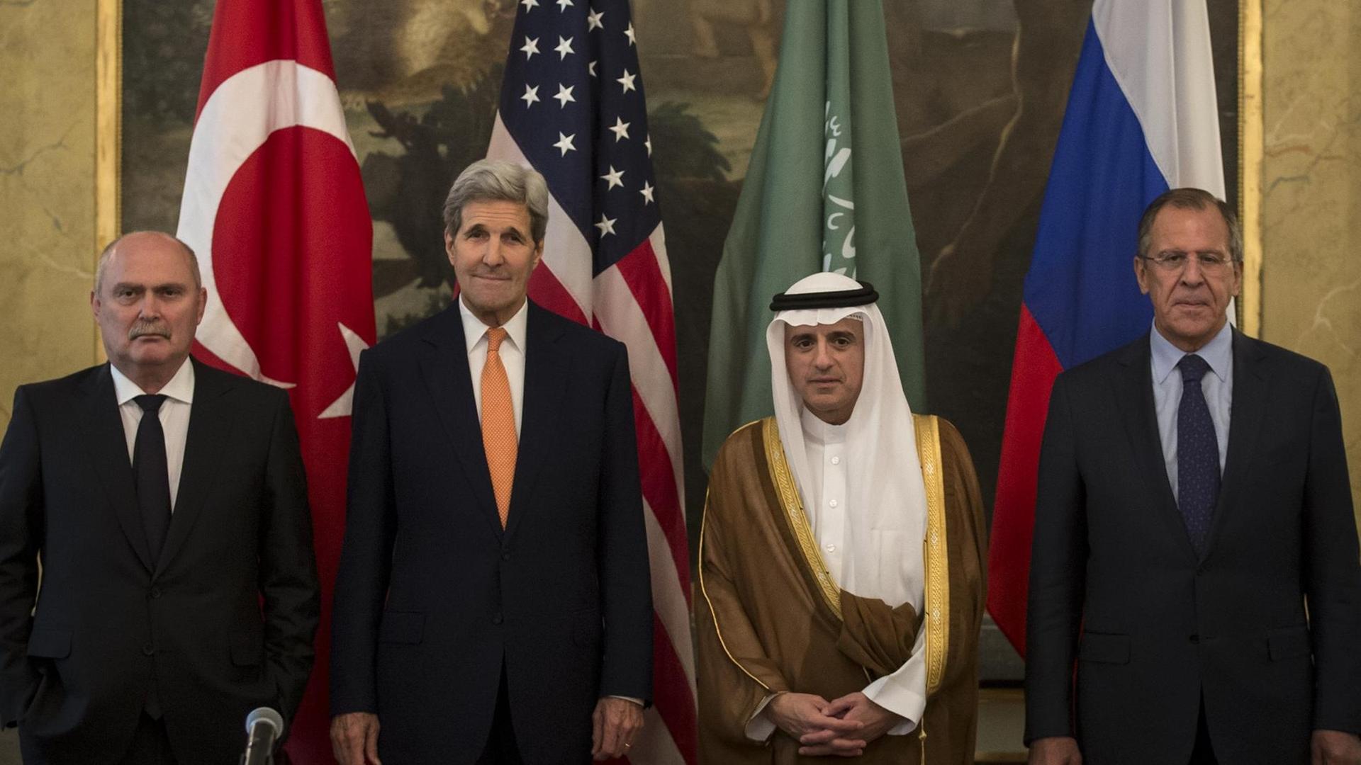Die vier Außenminister stehen in einem Raum nebeneinander vor den Flaggen ihrer Staaten, die wiederum vor einem Gemälde stehen. Der saudische Ressortchef trägt die traditionelle Kleidung seines Landes. Die vier Außenminister stehen in einem Raum nebeneinander vor den Flaggen ihrer Staaten, die wiederum vor einem Gemälde stehen. Der saudische Ressortchef trägt die traditionelle Kleidung seines Landes.