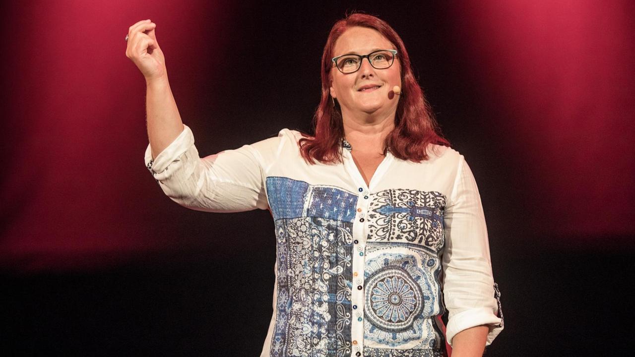 Die Kabarettistin Anny Hartmann steht auf einer dunklen Bühne Die Kabarettistin Anny Hartmann steht auf einer dunklen Bühne
