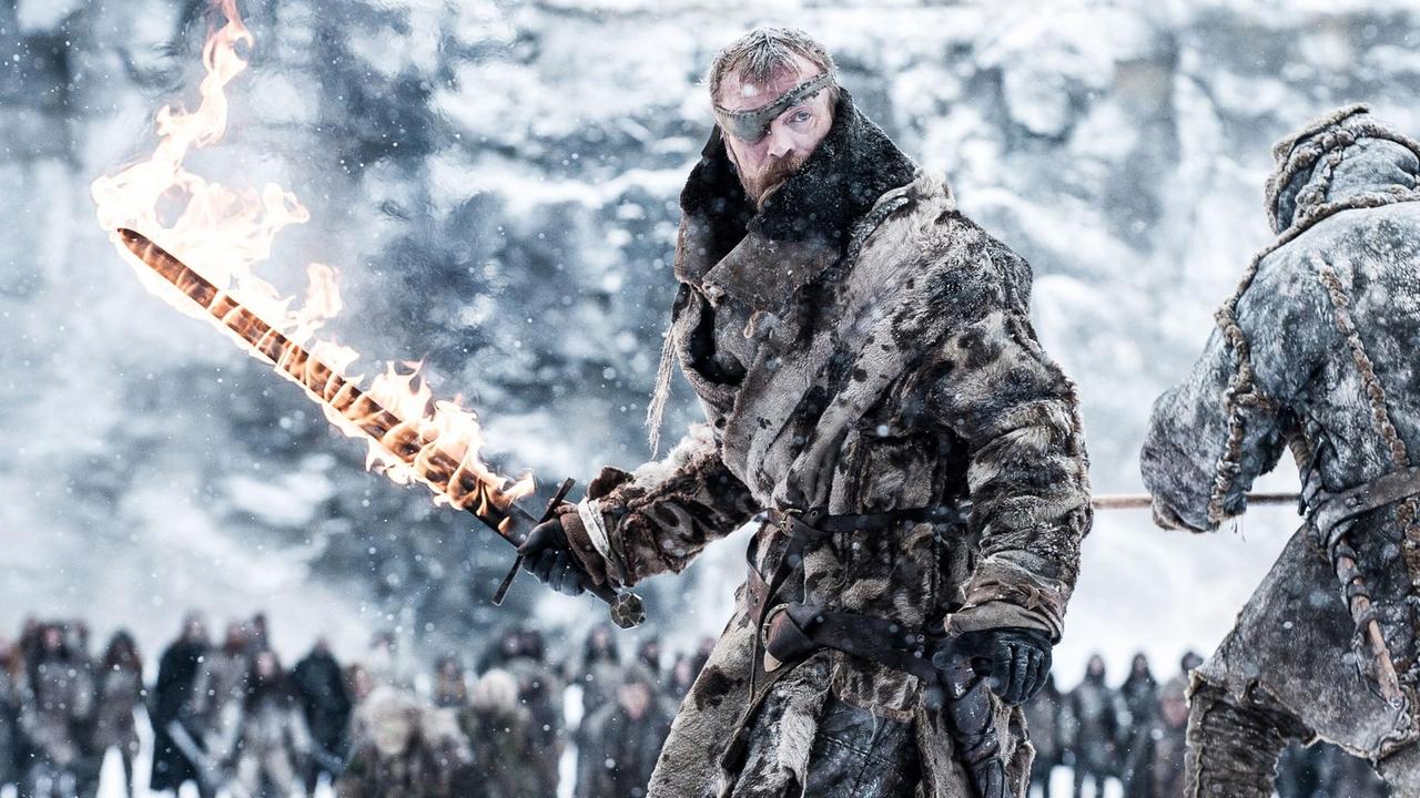 Ein "Game of Thrones"-Charakter mit Augenklappe steht in einer Eislandschaft und hält ein brennendes Schwert in der Hand Ein "Game of Thrones"-Charakter mit Augenklappe steht in einer Eislandschaft und hält ein brennendes Schwert in der Hand