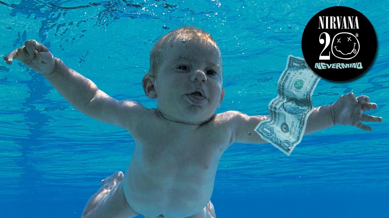 Ein nacktes Baby scheint unter Wasser einem Geld-Schein hinterher zu schwimmen.