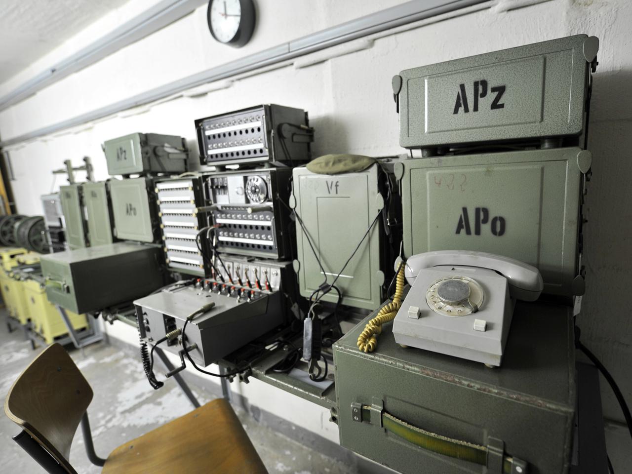 In einem Bunker sind an einer Wand ein Telefon und mehrere andere elektronische Geräte angebracht. In einem Bunker sind an einer Wand ein Telefon und mehrere andere elektronische Geräte angebracht.