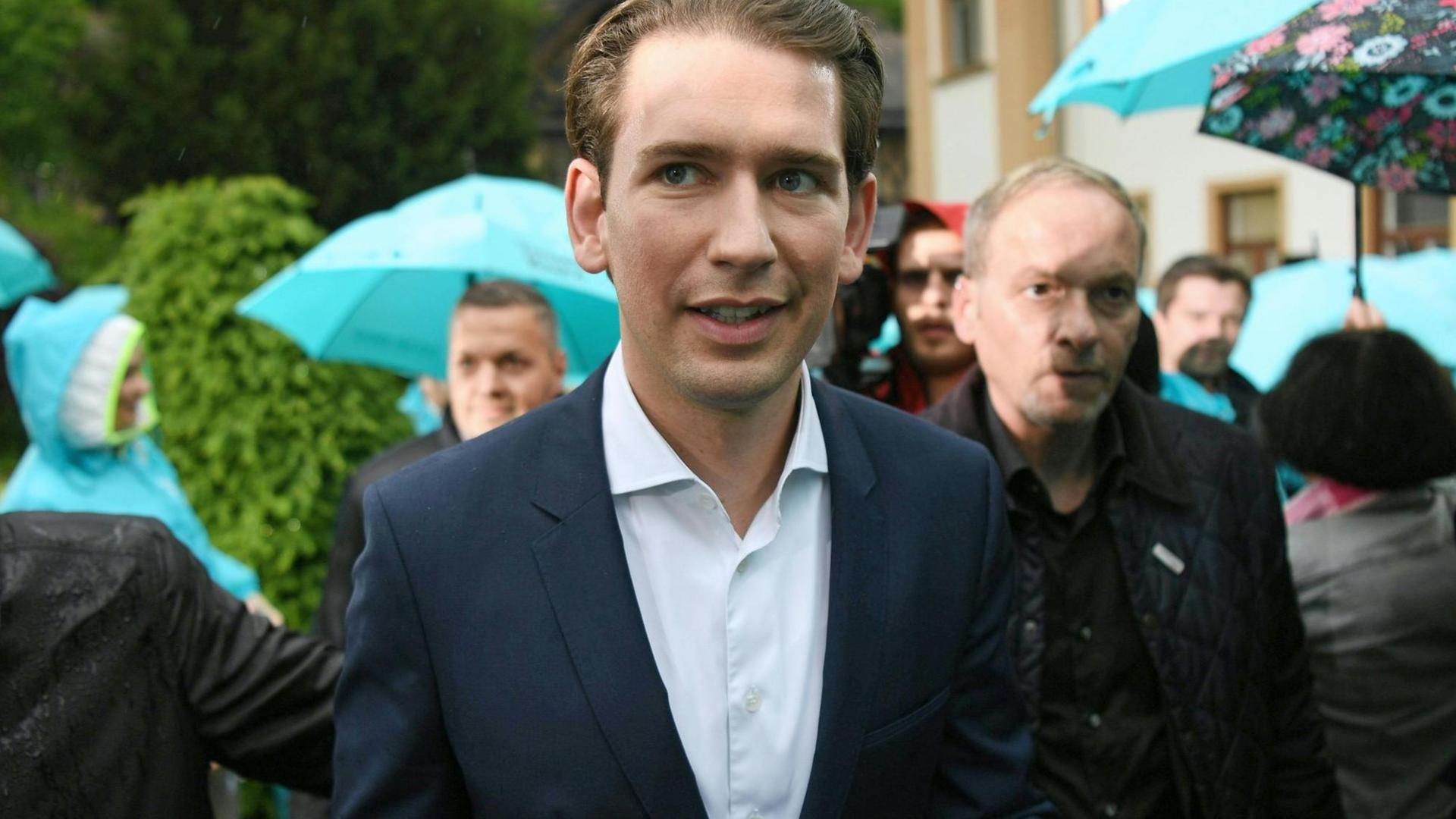 Österreichs Bundeskanzler Sebastian Kurz nach seinem Statement zum Misstrauensvotum, im Hintergrund mehrere Menschen mit türkisfarbenen Schirmen. Österreichs Bundeskanzler Sebastian Kurz nach seinem Statement zum Misstrauensvotum, im Hintergrund mehrere Menschen mit türkisfarbenen Schirmen.