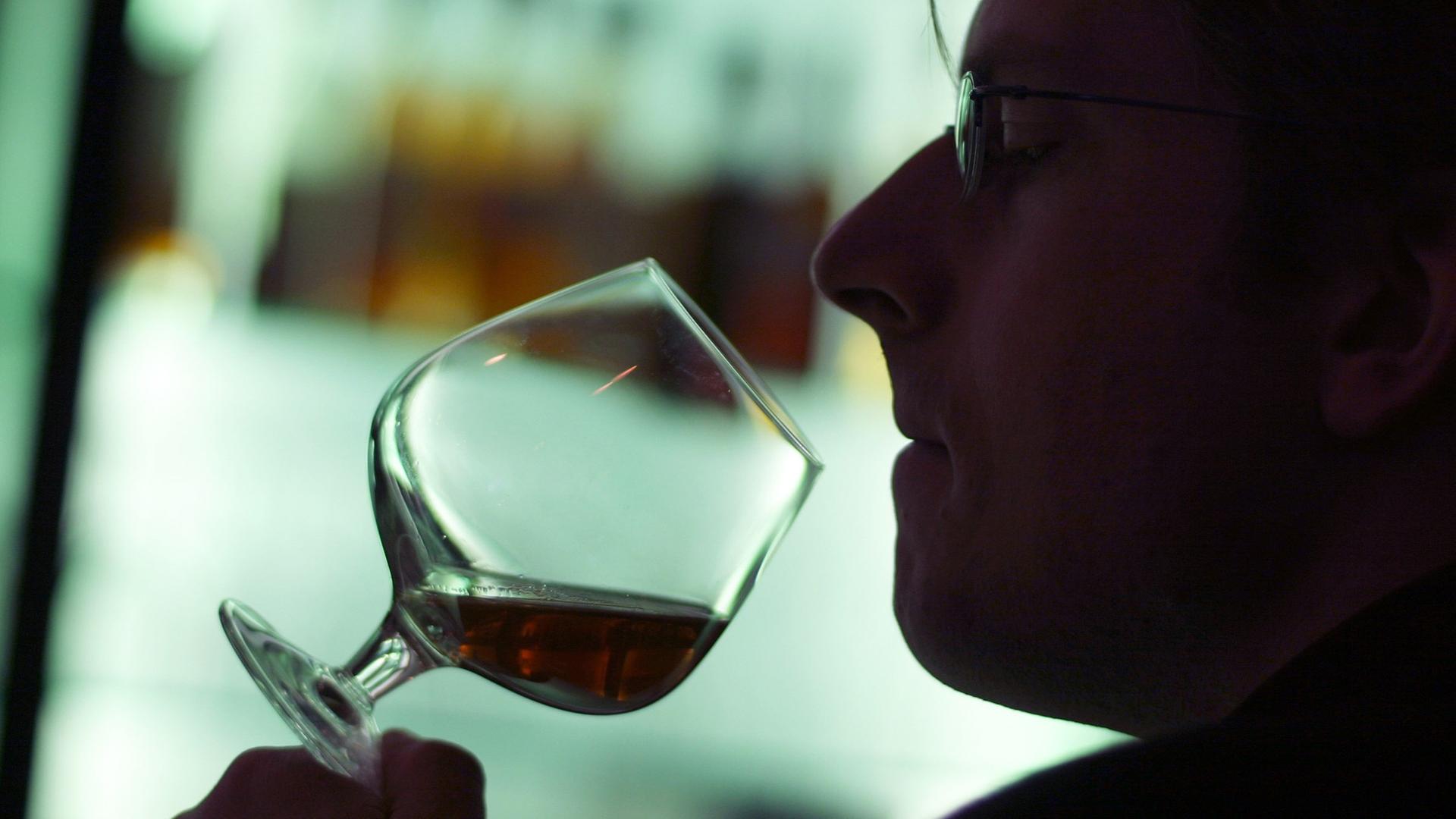 Ein Mann riecht an einem Glas Cognac in einer Hotelbar in München. Ein Mann riecht an einem Glas Cognac in einer Hotelbar in München.