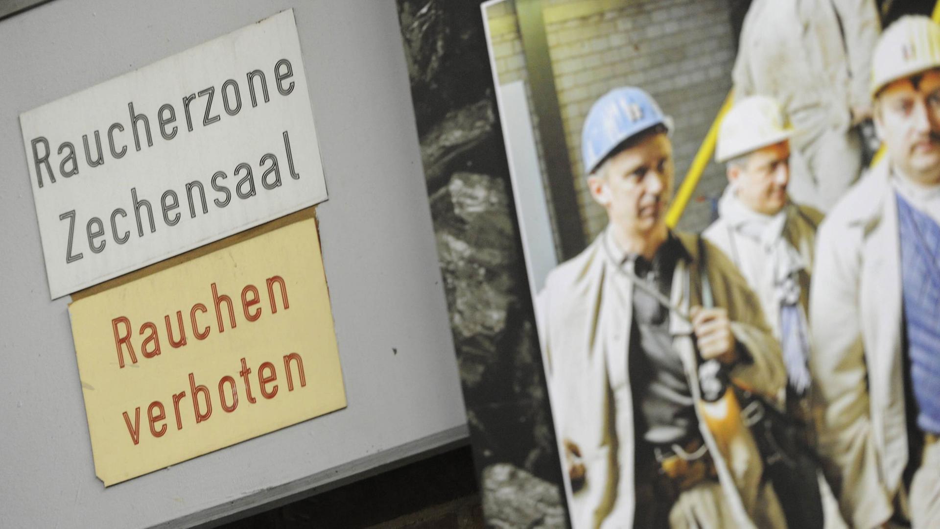 Im Bergwerk Saar der "RAG Deutsche Steinkohle" in Ensdorf im Saarland hängt neben zwei Schildern ein Foto mit ehemaligen Arbeitern