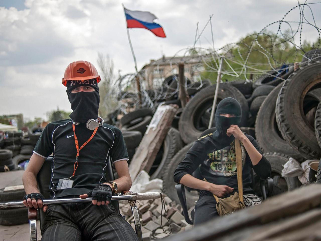Zwei vermummte pro-russische Demonstranten warten vor einer Barrikade in der Nähe der besetzen Regionalverwaltung in der ost-ukrainischen Stadt Donezk. Zwei vermummte pro-russische Demonstranten warten vor einer Barrikade in der Nähe der besetzen Regionalverwaltung in der ost-ukrainischen Stadt Donezk.