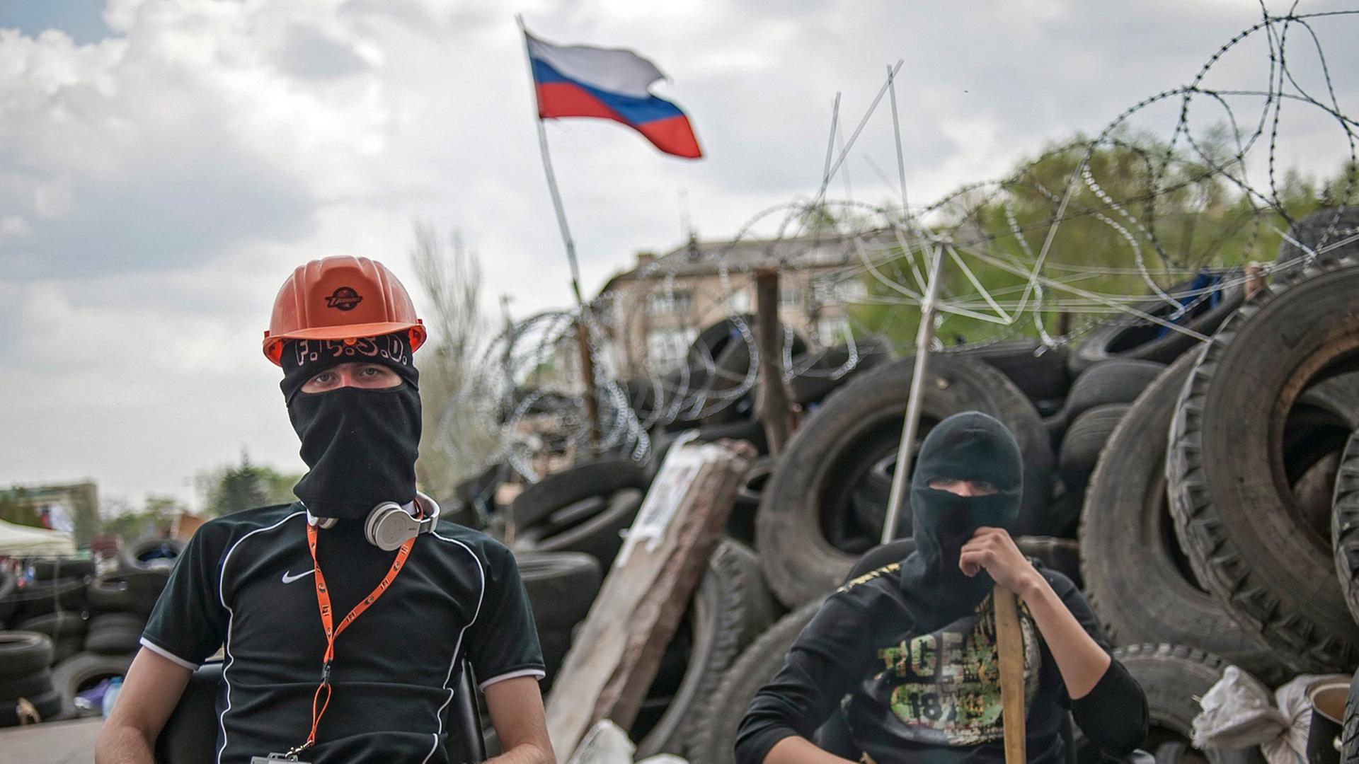 Zwei vermummte pro-russische Demonstranten warten vor einer Barrikade in der Nähe der besetzen Regionalverwaltung in der ost-ukrainischen Stadt Donezk. Zwei vermummte pro-russische Demonstranten warten vor einer Barrikade in der Nähe der besetzen Regionalverwaltung in der ost-ukrainischen Stadt Donezk.