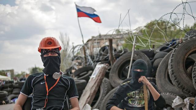 Zwei vermummte pro-russische Demonstranten warten vor einer Barrikade in der Nähe der besetzen Regionalverwaltung in der ost-ukrainischen Stadt Donezk.