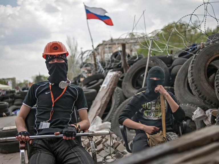 Zwei vermummte pro-russische Demonstranten warten vor einer Barrikade in der Nähe der besetzen Regionalverwaltung in der ost-ukrainischen Stadt Donezk.