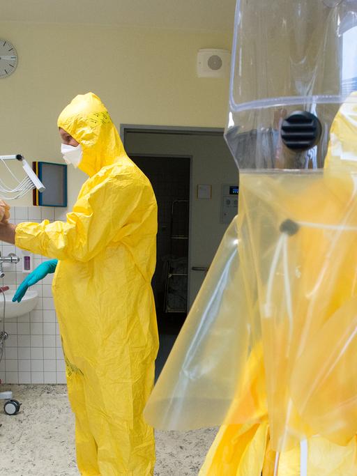 Im Bundeswehrkrankenhaus in Berlin stattet ein Soldat einen Freiwilligen mit einem Schutzanzug aus. Zweck: Eine Übung für Ebola-Helfer in Westafrika.