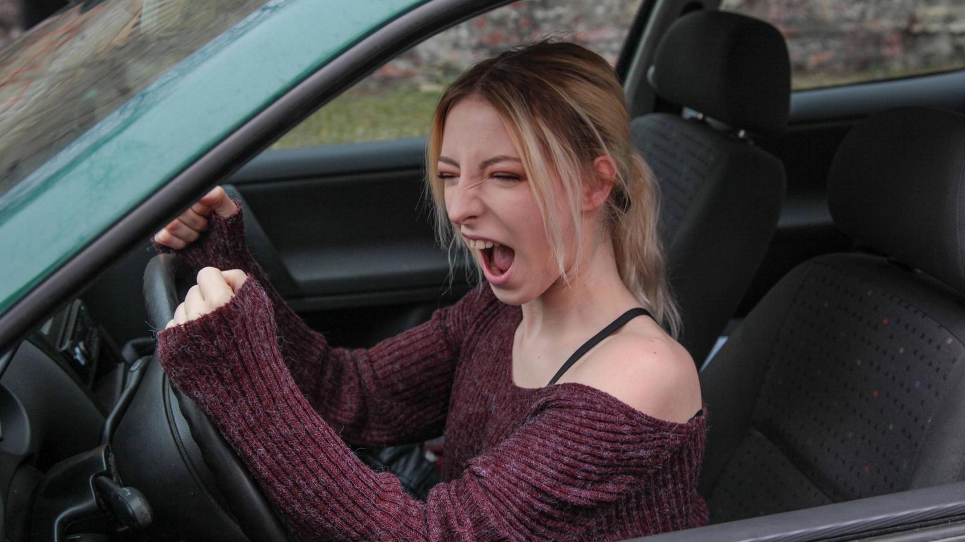 Eine junge Frau schimpft hinterm Autosteuer. Eine junge Frau schimpft hinterm Autosteuer.