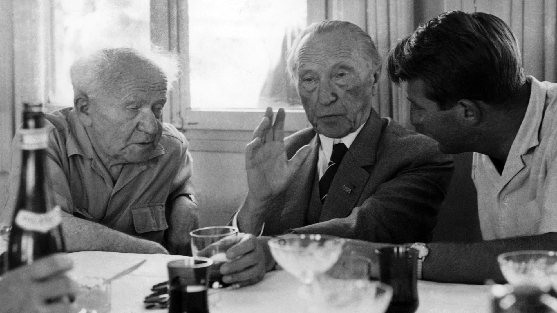 David Ben Gurion (l), der ehemalige israelische Premierminister, Bundeskanzler Konrad Adenauer (M) und ein Dolmetscher (r) am 09.05.1966 im Kibbuz Sede Bokar nach dem Mittagessen im Gespräch. Adenauer besuchte das Kibbuz während seines Staatsbesuches in Israel und bekam von Ben Gurion dessen neustes, in Großbritannien erschienenes Buch "The Jews in Their Land" mit einer persönlichen Widmung geschenkt. David Ben Gurion (l), der ehemalige israelische Premierminister, Bundeskanzler Konrad Adenauer (M) und ein Dolmetscher (r) am 09.05.1966 im Kibbuz Sede Bokar nach dem Mittagessen im Gespräch. Adenauer besuchte das Kibbuz während seines Staatsbesuches in Israel und bekam von Ben Gurion dessen neustes, in Großbritannien erschienenes Buch "The Jews in Their Land" mit einer persönlichen Widmung geschenkt.