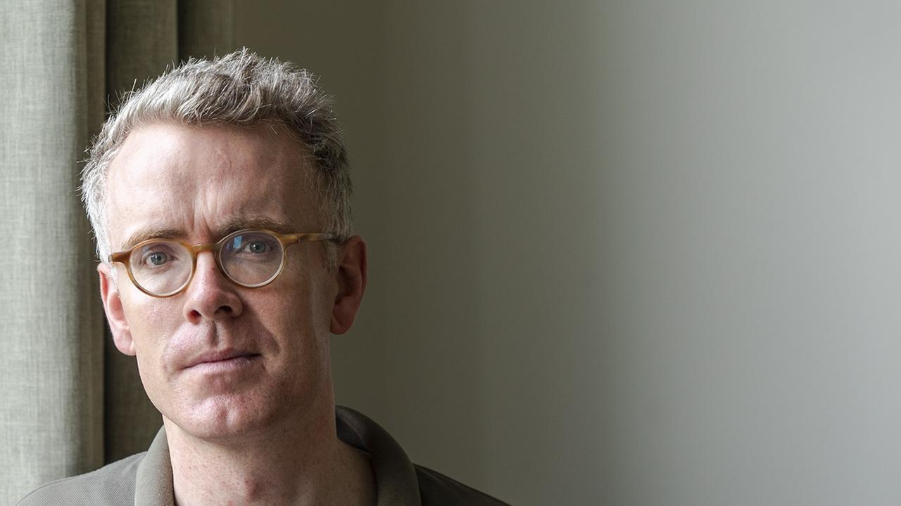 Derek Scally trägt Brille, steht am Fenster und schaut in die Kamera. Derek Scally trägt Brille, steht am Fenster und schaut in die Kamera.