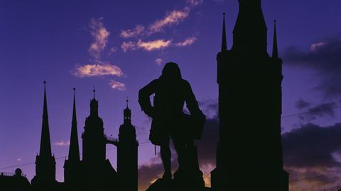 Silhouetten des Händeldenkmals, der Türme der Marktkirche und des Roten Turms vor Abendhimmel.