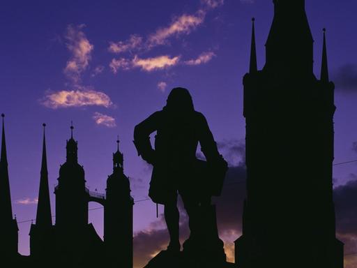 Silhouetten des Händeldenkmals, der Türme der Marktkirche und des Roten Turms vor Abendhimmel.