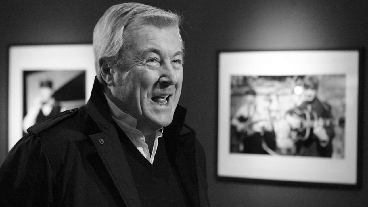 Ein Schwarzweißfoto von Terry O'Neill vor seinen Werken. Ein Schwarzweißfoto von Terry O'Neill vor seinen Werken.