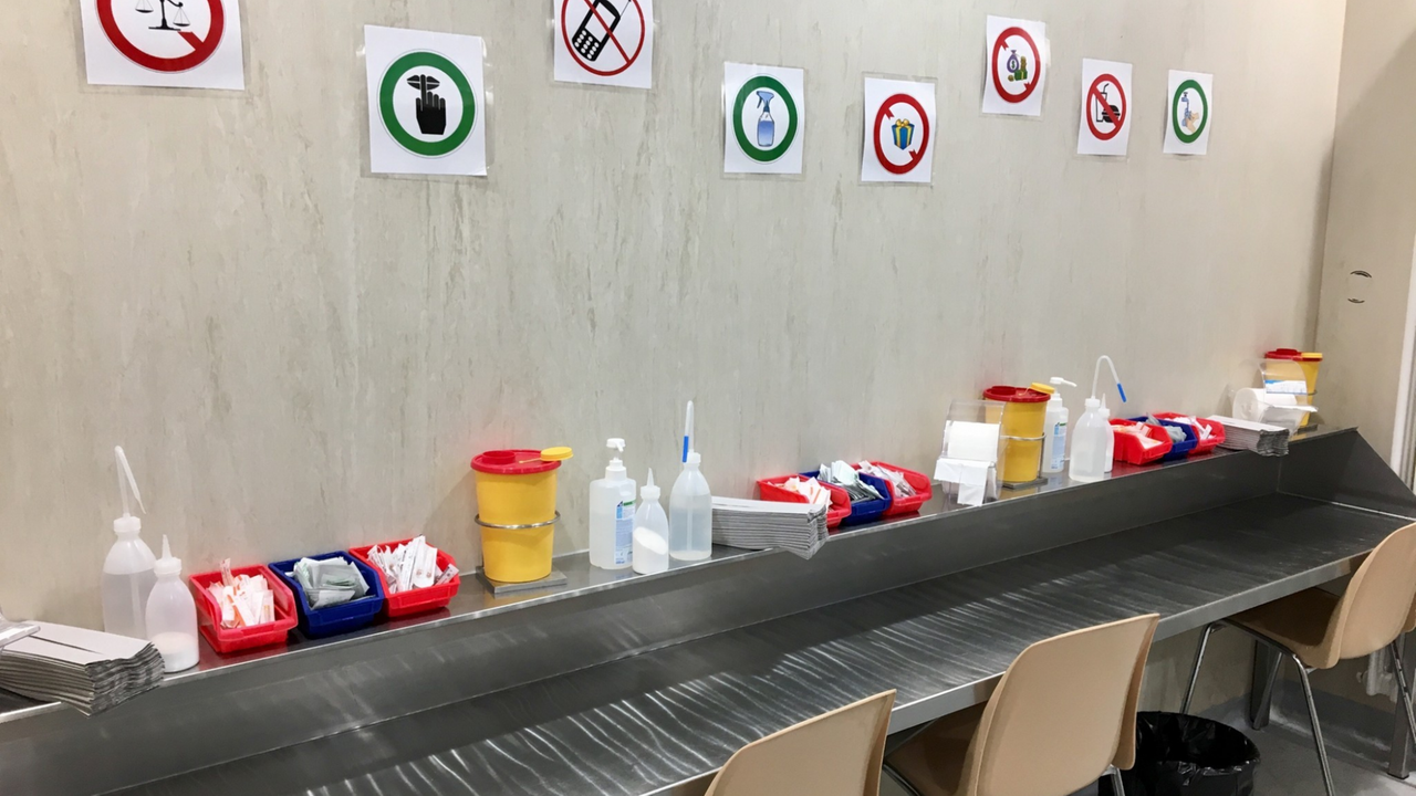 Ein Tisch mit Sitzgelegenheiten und Hilfsutensilien zum hygienischen Gebrauch des Drogenbestecks. An der Wand hängen Hinweise, wie sich die Klienten verhalten sollen.