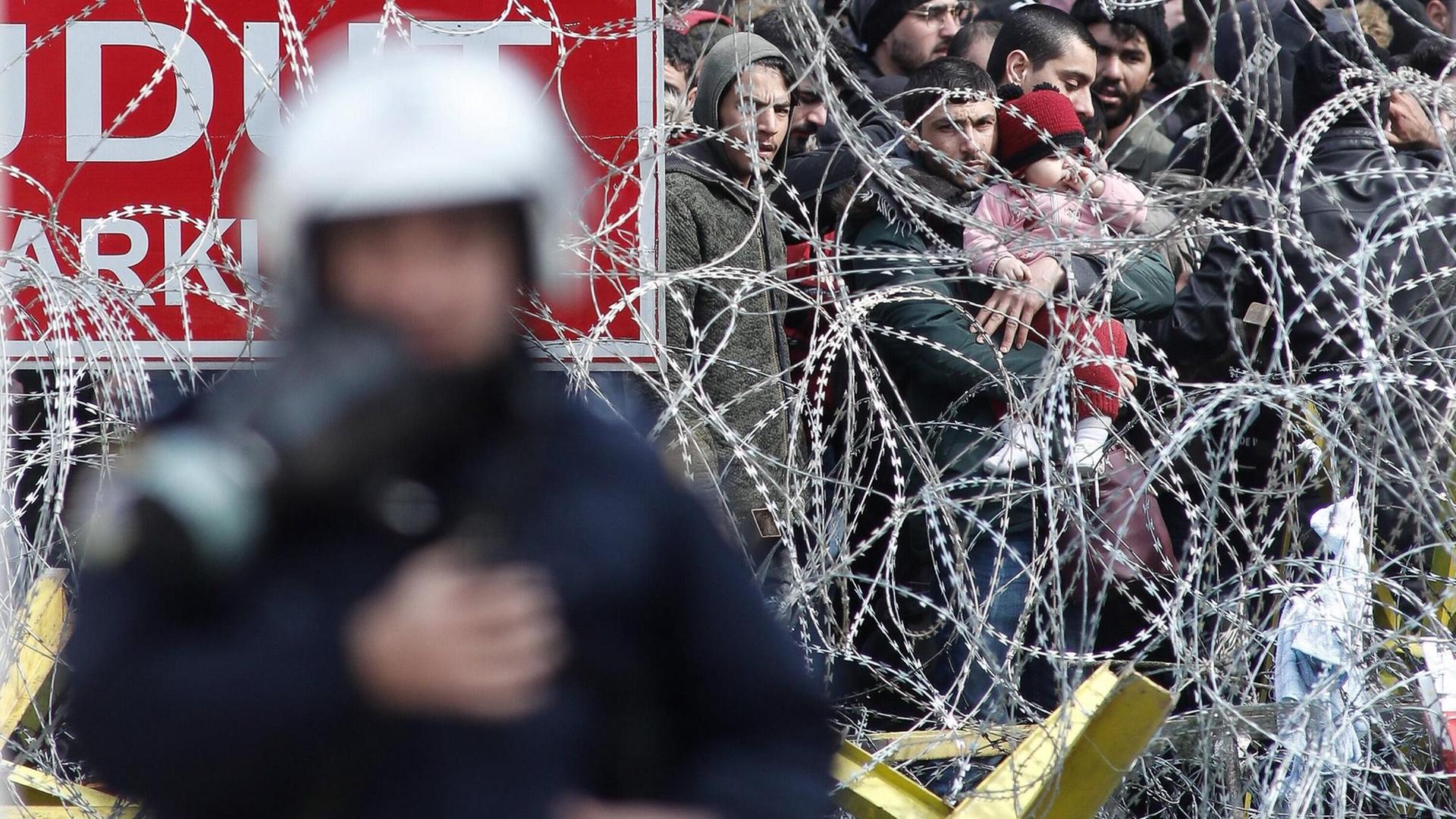 Flüchtlinge hinter einem Stacheldrahtzaun an der griechisch-türkischen Grenze Flüchtlinge hinter einem Stacheldrahtzaun an der griechisch-türkischen Grenze