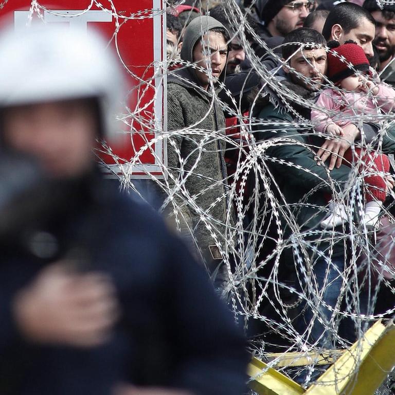 Flüchtlinge hinter einem Stacheldrahtzaun an der griechisch-türkischen Grenze